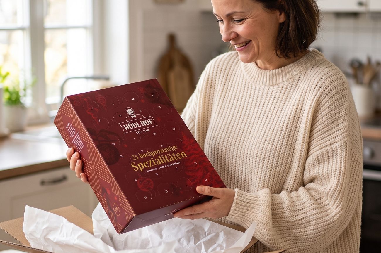 Eine Frau hebt den Adventkalender morgens am Küchentisch aus einem Versandkarton.