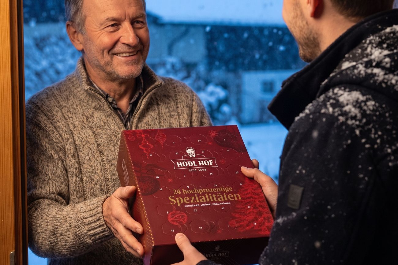 Ein Sohn überreicht seinem Vater an der Haustür den Adventkalender, draußen schneit es.