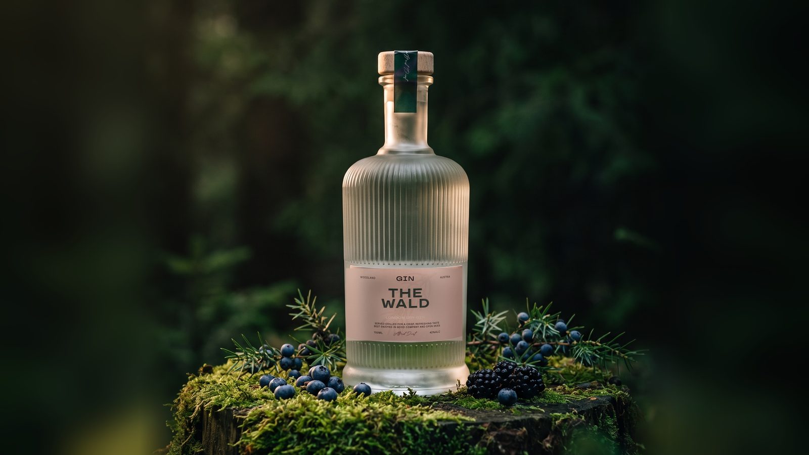 Flasche The Wald Austrian Dry Gin auf einem moosbewachsenen Baumstumpf im Wald