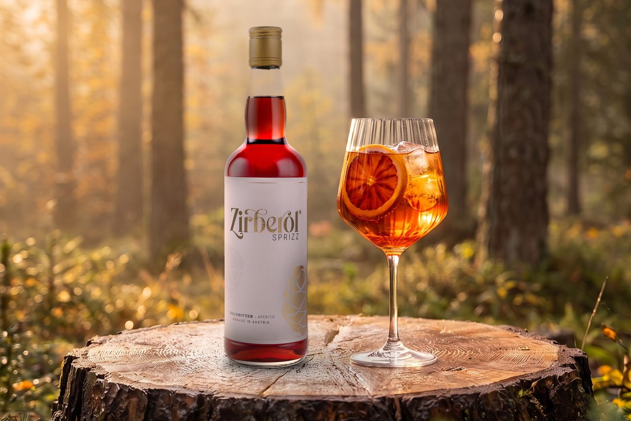 Zirberol Sprizz und ein Glas Sprizz auf einem Baumstumpf im herbstlichen Wald